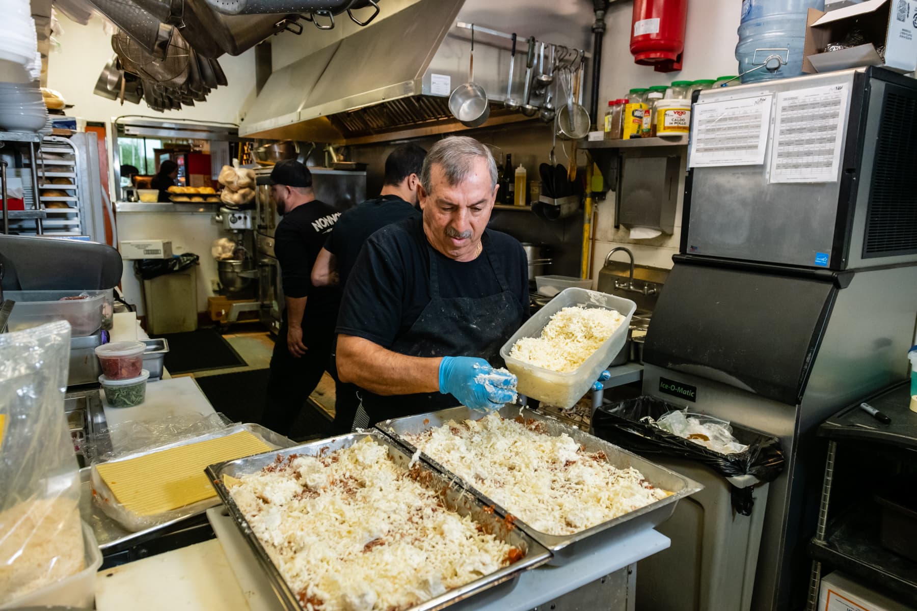 Stefano adding cheese to trays of lasagna in the Nonno's kitchen